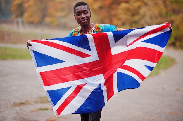 African man in africa traditional shirt on autumn park with Great Britain flag.