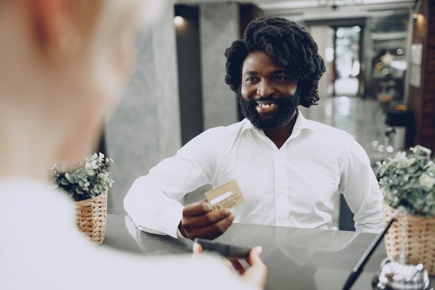 Photo african man businessman paying for the stay in hotel with credit card