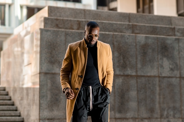 대도시를 걷고 있는 우아한 세련된 정장을 입은 아프리카 남자.