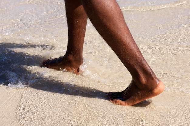 African man feet walking on the beach