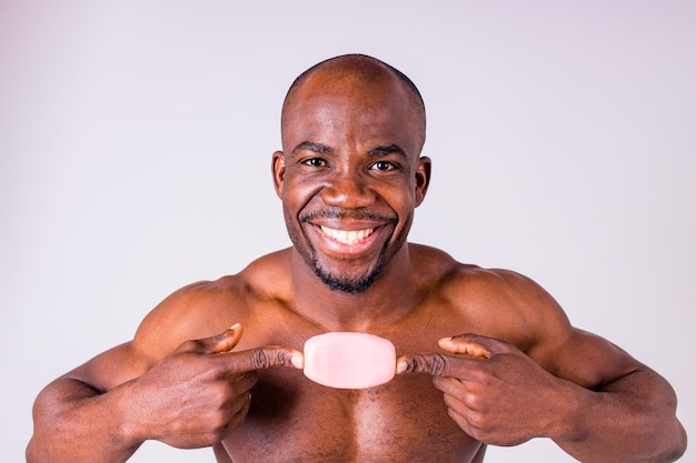 African man holds and show a piece of wet soap in studio white background