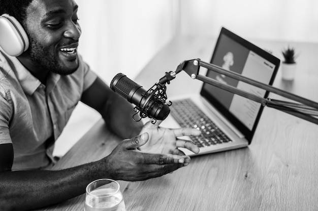 African man live streaming podcast session at home studio - Focus on microphone