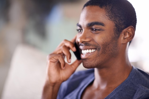 African man phone call and home on sofa with smile for conversation contact and listening in lounge Person smartphone and happy for mobile connection talking and chat on couch in house