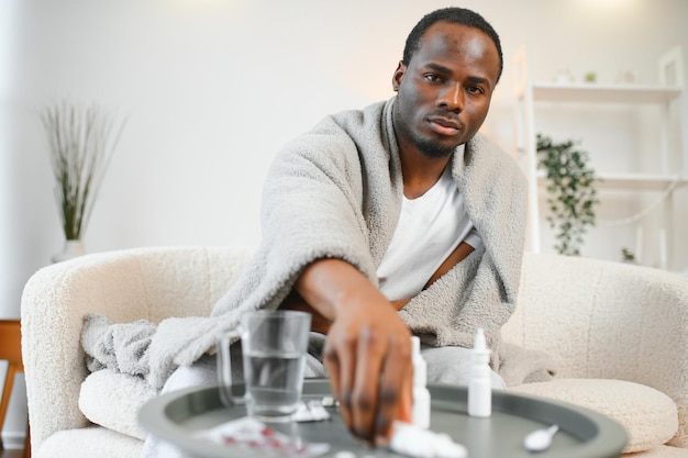 Photo an african man sick with croup or a cold is covered with a blanket at home