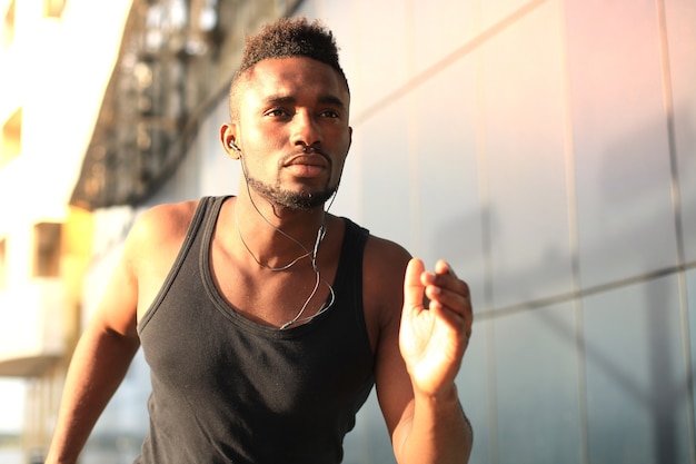 Photo african man in sports clothing running while exercising outdoors, at sunset or sunrise. runner.