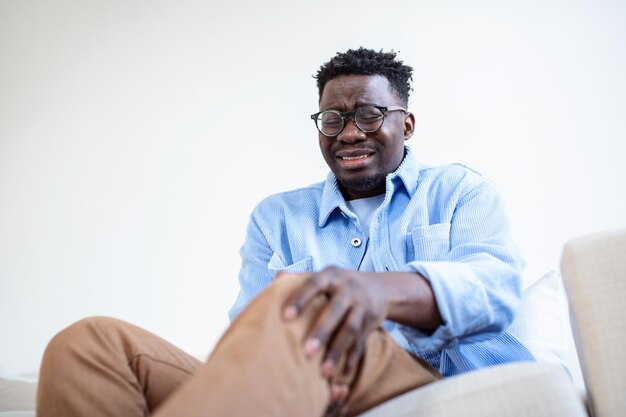 african man touching his knee by the pain during the day man massaging his painful knee