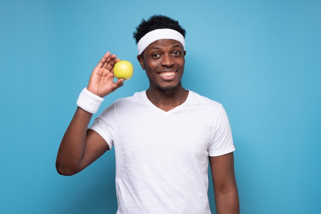 African man with muscles holding green apple taking care of his body dieting