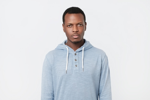 African man with serious expression looking at camera while posing against white studio wall