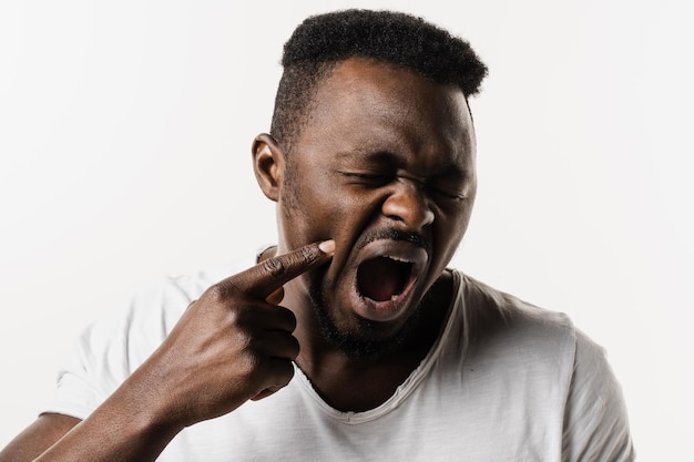 Photo african man with tooth decay infection or injury to the tooth or gums on white background african american man is touching cheek and feeling toothache pain and discomfort of tooth