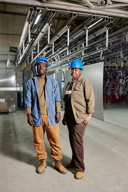 African manual workers in hardhats at factory