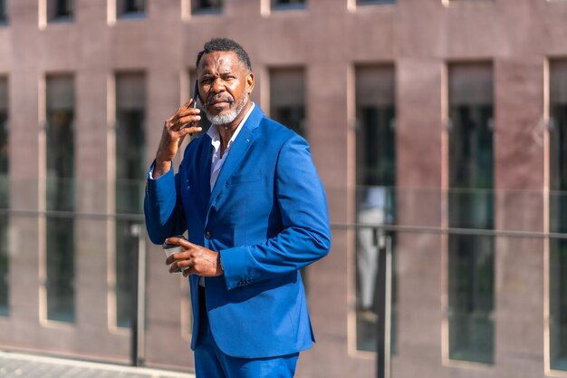 Африканский зрелый бизнесмен разговаривает по мобильному телефону на открытом воздухе
