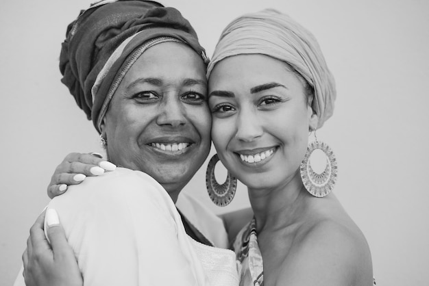 African mother and adult daughter hugging each other while wearing traditional dress and head scarf