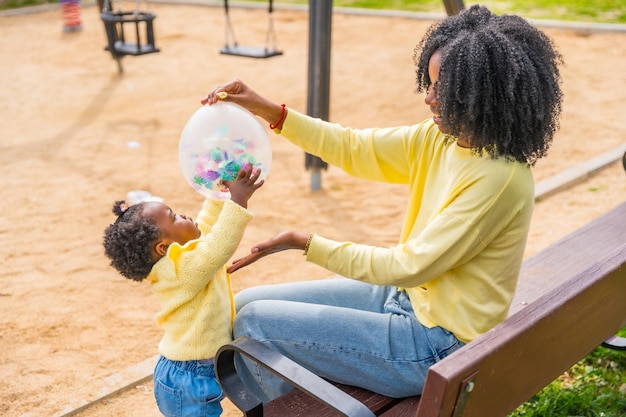 African mother and daughter playing with a balloon outdoors