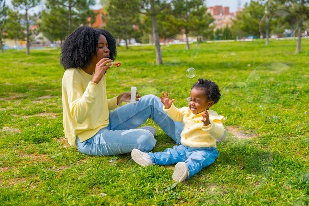 African mother and girl on the park making soap bubbles