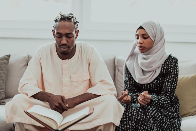Африканская мусульманская пара дома в Рамадане читает священную книгу Ислама Корана. Качественное фото