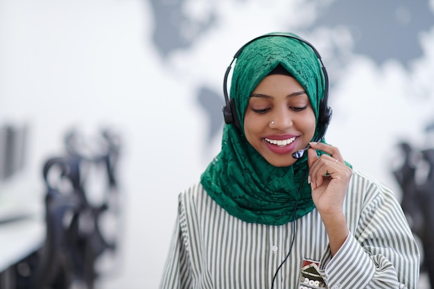 African muslim female with green hijab scarf customer representative business woman with phone headset helping and supporting online with customer in modern call centre