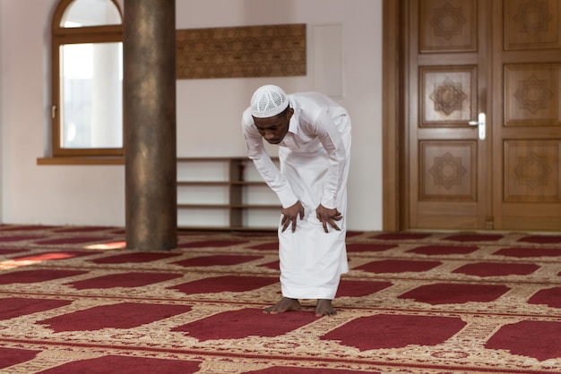 African muslim man making traditional prayer to god while wearing a traditional cap dishdasha