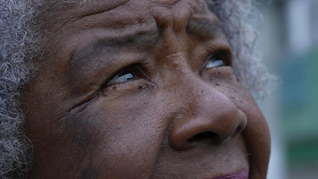 An african older woman looking up at sky with hope and faith\
macro eyes face closeup