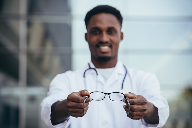 Photo african ophthalmologist doctor offers glasses looking into the camera