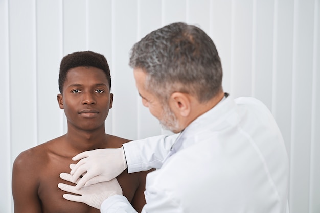 Фото Африканский пациент с голым торсом на осмотре у врача