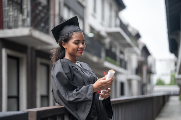 African people students man and woman with black graduation gowns hold the diploma and stand together With the feeling of happy and graceful