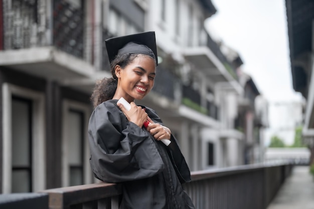 African people students man and woman with black graduation gowns hold the diploma and stand together With the feeling of happy and graceful