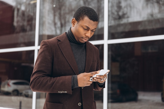 Афро-портрет красивый афро-американский бизнесмен с помощью смартфона.