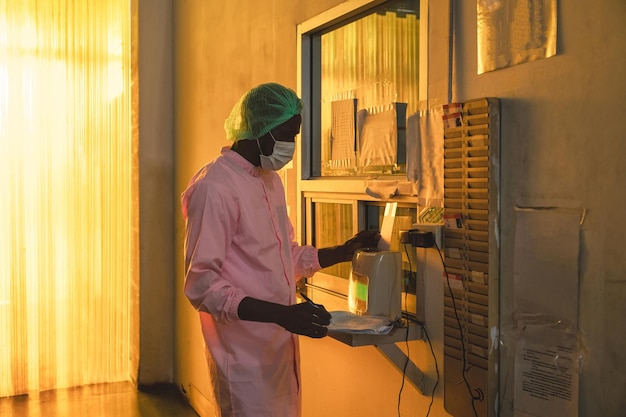 African quality control employee man in sterile suit clock in\
with time clock system of factory policy before working in\
processing warehouse