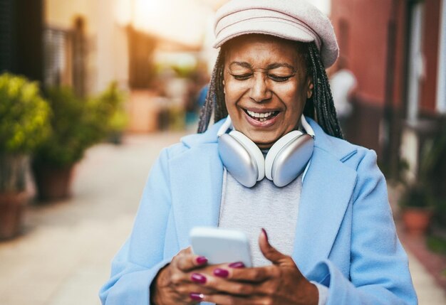 Photo african senior woman using mobile phone outdoor during winter time focus on face