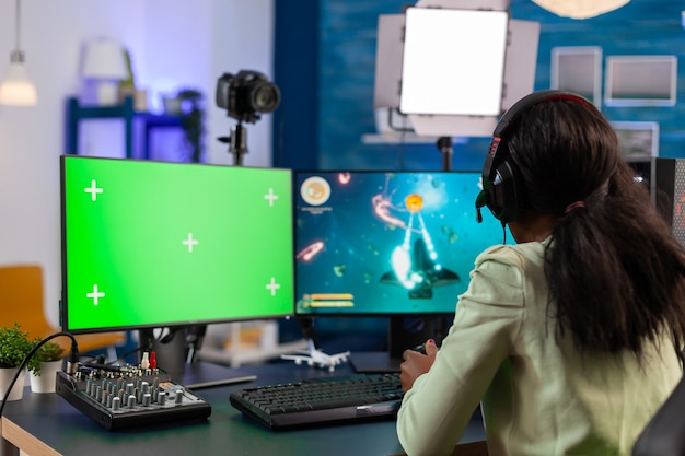 Flussi di giocatori di strategia africana utilizzando il computer per gli sport elettronici con chiave cromatica di notte parlando con più giocatori. giocatore che utilizza un pc con videogiochi sparatutto in streaming desktop isolati con schermo verde.