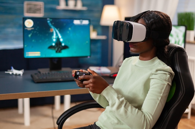 African streamer gamer experiencing virtual reality wearing
headset. virtual space shooter game championship in cyberspace,
esports player performing on pc during gaming tournament.