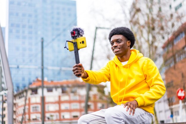 Photo african streamer using phone to stream in the city