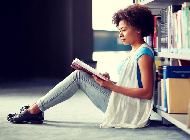 Photo african student girl reading book at library