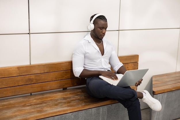 Foto studente africano in cuffia con il computer portatile