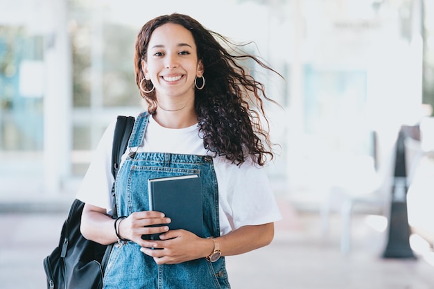 勉強の後に本を運ぶバックパックを持つアフリカの学生。若いアフリカの女性の肖像画。教育の概念。トレンディなファッションスタイル、バックパック、コピースペースを保持します。カメラに微笑む