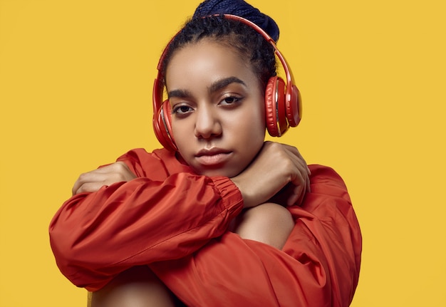 African teenage girl with dreadlocks in red windbreaker listening music