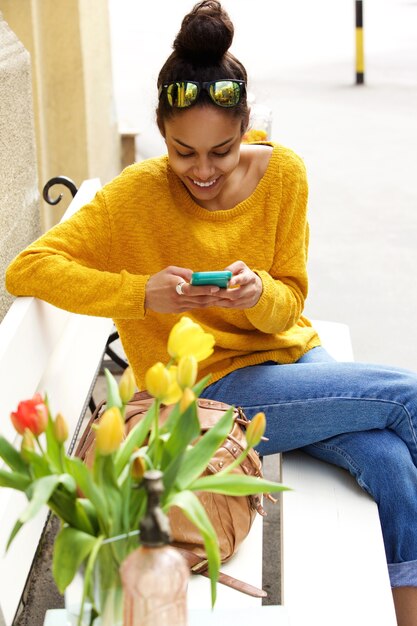 African woman on bench using cell phone