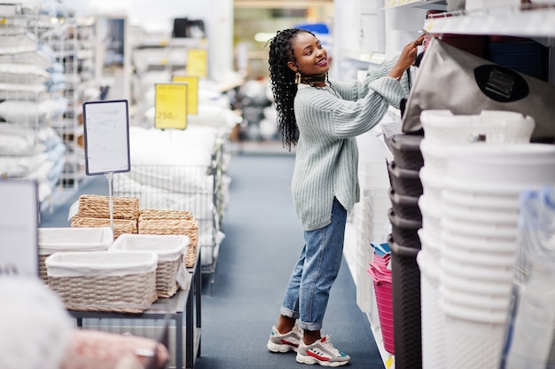 African woman choosing things for her apartment in a modern home furnishings store.