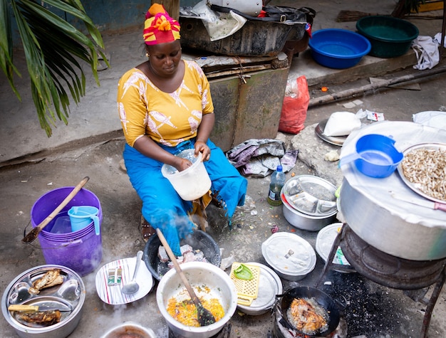 African woman cooking traditional food at street