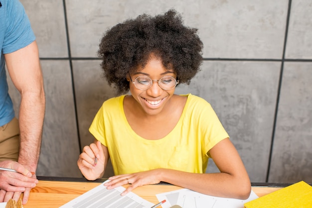 African woman dressed casually studying or working with documents indoors