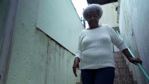 An African woman going down the stairs opening home gate and leaving house to urban sidewalk street