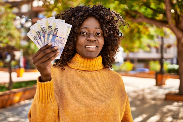 African woman holding bank notes outdoor