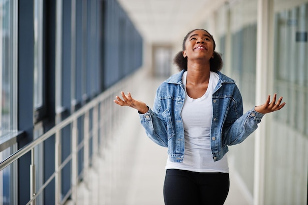 African woman in jeans jacket pray indoor.