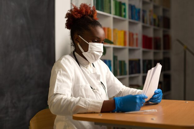 african woman in medical clothes at the table with documents