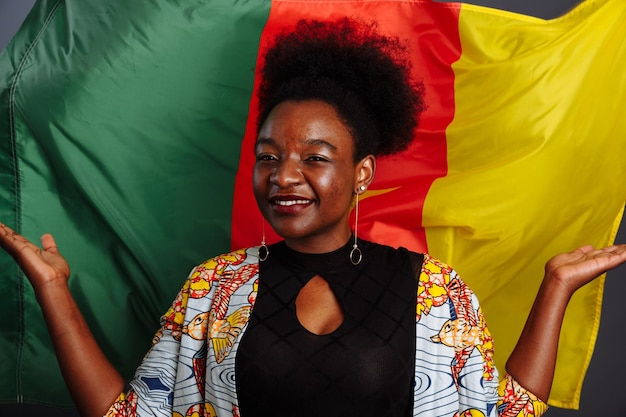 African woman in national clothes posing and dancing against flag of Cameroon