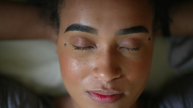Африканская женщина открывает глаза в камеру улыбающееся портретное лицо, лежащее в постели и смотрящее в камеру