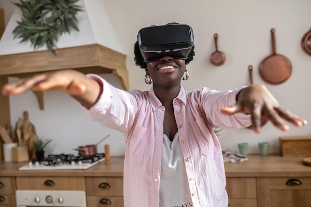 African woman in pink clothes in vr glasses looking excited