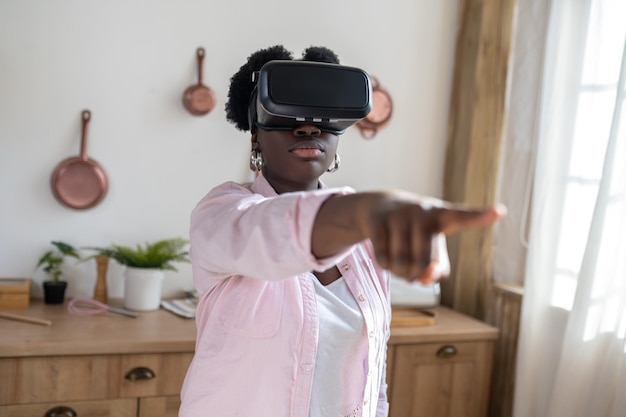 African woman in pink clothes in vr glasses looking excited