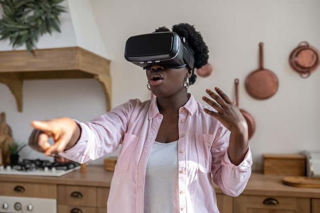 African woman in pink clothes in vr glasses looking excited