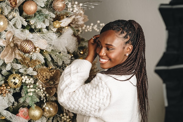 Foto donna africana che si prepara per le vacanze invernali decorando l'albero di natale